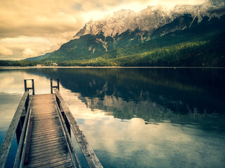 lake and mountains with pier and reflection while sun makes beautiful light