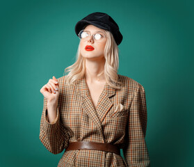 woman in British style jacket and hat on green background