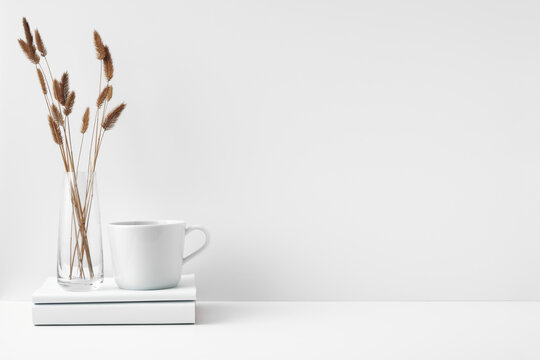 Fototapeta Mug and transparent vase with flowers on a white background. Eco-friendly materials in the decor of the room, minimalism. Copy space, mock up