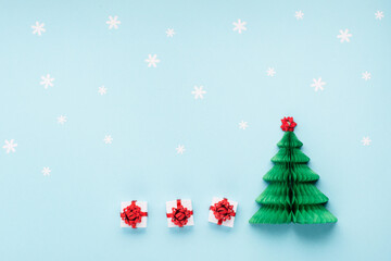 Christmas card - Xmas paper green tree, snowflakes and gift boxes on blue background.
