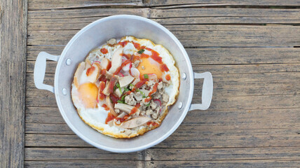 Top view picture of Vietnamese fried eggs in an aluminum dish placed on a wooden table.