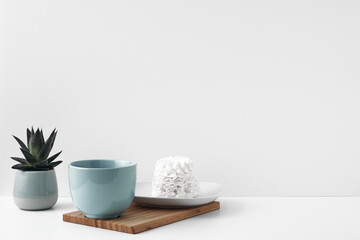 Blue mug and meringue cake on a white background. Eco-friendly and natural materials in decor and interior design, dessert. Copy space, mock up.