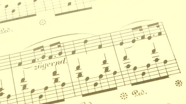 Hand turning pages of an old yellowed sheet music, simple piano musical score paper book detail, macro, extreme closeup, notes, notation seen from up close