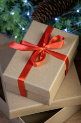 close-up of christmas gifts, two cardboard present boxes, red ribbon and bow, vintage bright decoration with wreath, lights and cone, view from above