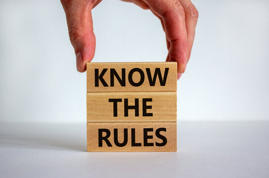Know the rules. Wooden blocks tower with words 'know the rules', male hand. Beautiful white background. Copy space. Business and know the rules concept.