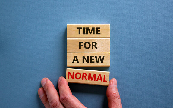 Time for a new normal. Wooden blocks with words 'time for a new normal'. Male hand. Beautiful blue background. Copy space. Business and new normal concept.