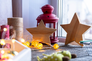 Two wooden stars, a red candlestick lantern, a garland on the window.