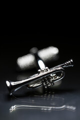 Trumpet cufflink on a reflective background