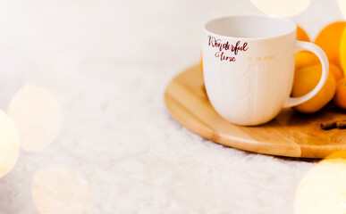 Obraz na płótnie Canvas A white cup with the inscription Wonderful Winter stands on a wooden tray, pallesins and cinnamon lie next to it. The tray is on a soft white carpet