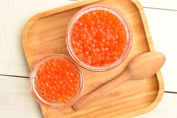 Red caviar with , closeup, on a  wooden table.