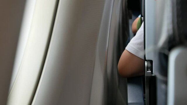 Arm rest on armrest while sitting in airplane near window seat