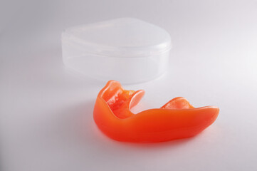 Orange mouthguard with transparent case on the white background