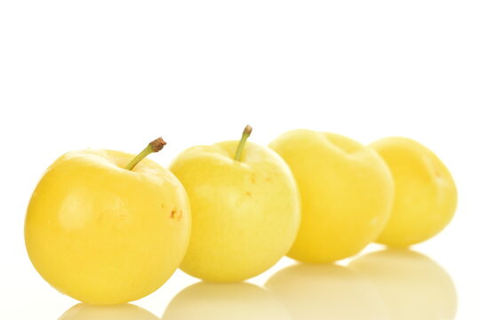 Several juicy bright yellow plums, close-up, on a white background.