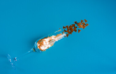 Champagne glass with glitter confetti on a blue background. Invitation to a party. The concept of...