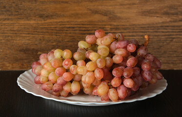 a bunch of pink grapes on a white dish