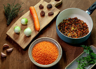 Cooking red lentil and dried apricot soup. Ingredients on wooden board, plates and pan.