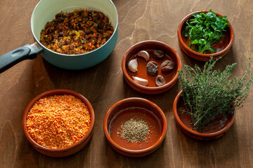 Cooking red lentil and dried apricot soup. Ingredients on wooden board, plates and pan.