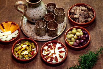 Set of tapas appetizers prepared at home in ceramic bowls. Ceramic jug and cups for drinks.