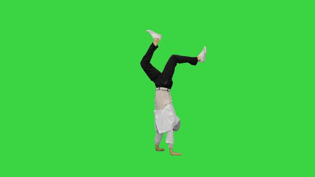 Male doctor in white robe and protective cap dancing breakdance on his head and arms on a Green Screen, Chroma Key.