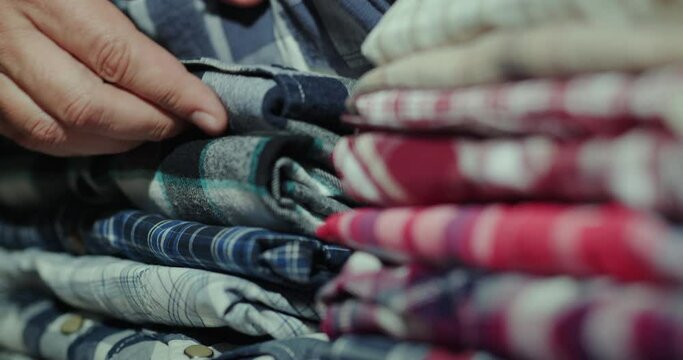 Men's hands sort clothes in a stack on the shelf