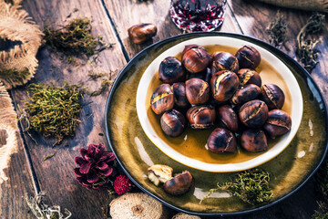 Roasted chestnuts for Christmas served on a wooden table with red mulled wine