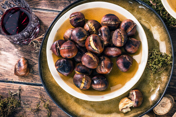 Roasted chestnuts for Christmas served on a wooden table with red mulled wine