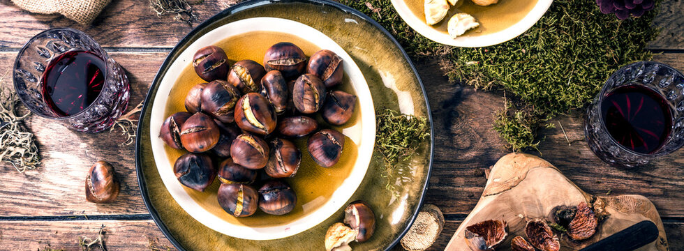 Roasted chestnuts for Christmas served on a wooden table with red mulled wine
