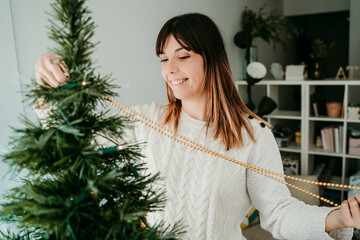 .Happy young woman preparing her house for Christmas time. Decorating your tree with pretty Christmas balls. Lifestyle