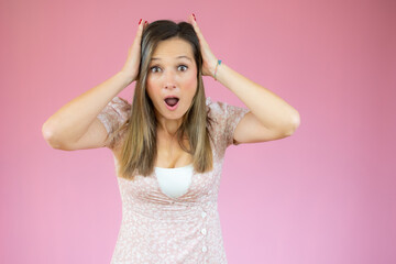 Fototapeta premium Image of excited screaming shocked beautiful woman standing isolated over pink background.