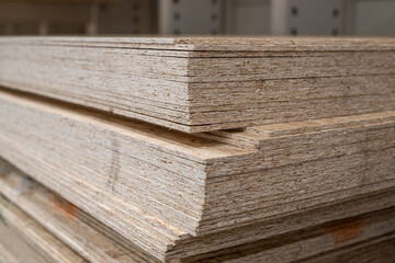 OSB sheets are stacked in a hardware store. The building material is wood.