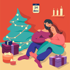 A man and a women are sitting on floor close to christmas tree