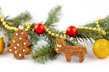 Homemade gingerbread in shape of Christmas tree decorated with sugar balls with Christmas branch on background with gold and red balls. Copy space. Banner