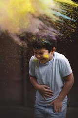 Portrait of European happy boy playing with Holi colors.