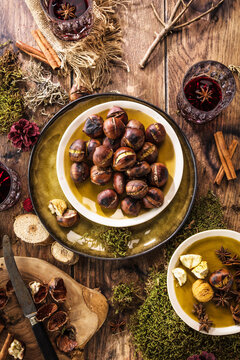 Roasted chestnuts for Christmas served on a wooden table with red mulled wine