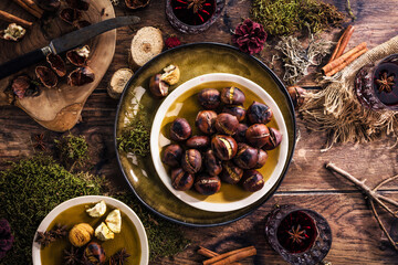 Roasted chestnuts for Christmas served on a wooden table with red mulled wine