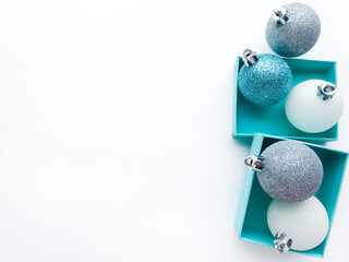 Turquoise jewel boxes inside of which is a shiny Christmas balls white, blue and silver color on the right. White background. Copy space