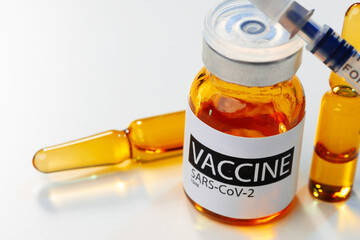 Sars-cov-2 vaccine vial and syringe on white table