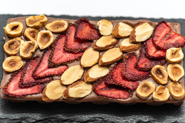Chocolate bar with the addition of fruit nuts on background. Dessert food concept.
