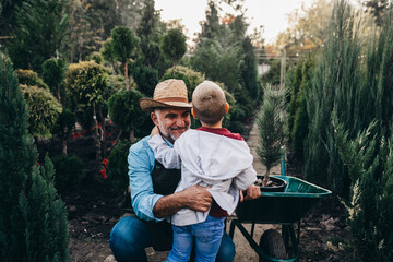 grandson with his grandfather working in plant nursery