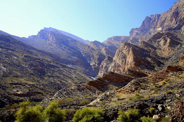 Fototapeta na wymiar Mountains with unidirectional rocks fractures and grass area, Wadi Bani Awf, Al Rustaq, South Batinah Governorate of Oman