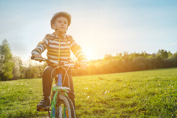 Child on bike in park. Boy going wearing safe bicycle helmets. Little Kid biking on sunny summer day. Active healthy outdoor sport Fun activity.
