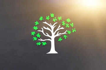 Tree with a crown of green puzzles on a dark background. Creativity, development, team work.