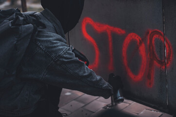 Process of making stop sing graffiti on the abandoned wall by anonymous young punk protester. 