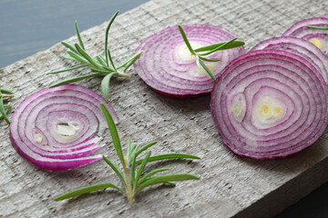 Red sliced onion and rosemary on a wooden background.