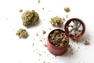 Cannabis branch, joint and red grinder isolated in a white background. Marijuana legalization. Medical cannabis. Drug addiction.	