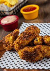 Baked chicken wings with sesame and sauce on wooden background