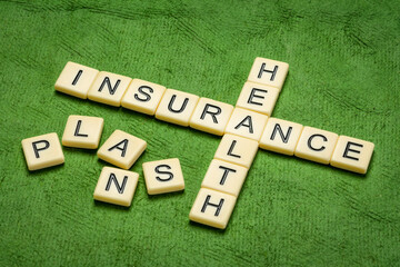 health insurance plans crossword in ivory letter tiles against textured handmade paper, healthcare concept
