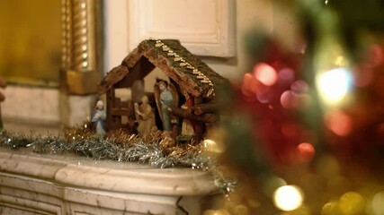 Woman puts miniature figurines of Mary in a christmas crib above the fireplace. Beautiful nativity scene and christmas decorations - close view
