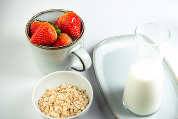 a beautiful mug of gray-blue color with strawberries, a gray-blue tray and a bowl with grains of oatmeal on a white background. horizontal photo. Frontal composition