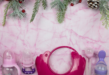 Children's accessories lie on pink marble and with Christmas tree branches. Place for text
